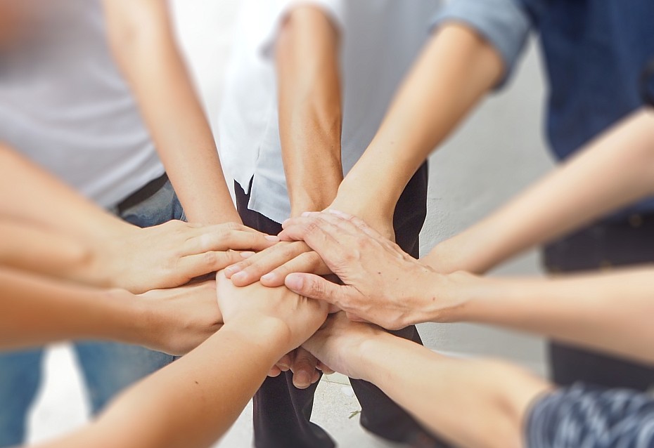 Menschen halten ihre Hände zusammen - ein Symbol für Teamwork