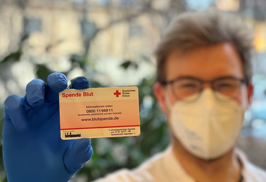 Mitarbeiter zeigt Blutspendeausweis