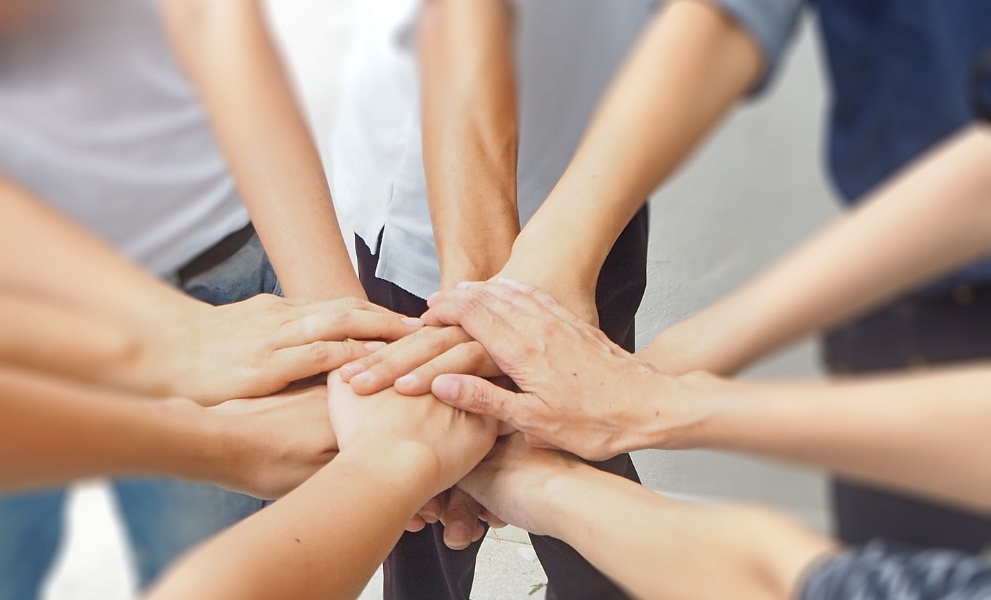 Menschen halten ihre Hände zusammen - ein Symbol für Teamwork