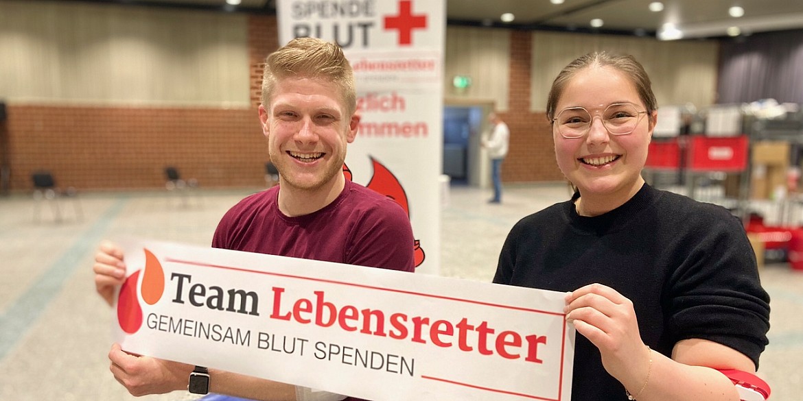 Zwei Spender halten den Team-Lebensretter Banner