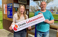 Eine Frau und ein Mann halten den Team-Lebensretter Banner